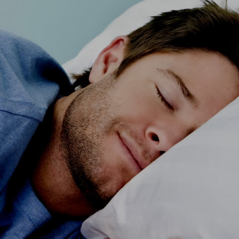 Man sleeping peacefully with a blue shirt on a light blue background