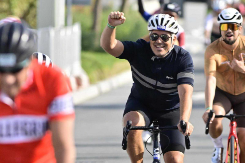 Cyclist celebrating on a road with other cyclists in the background - Damian apmzee
