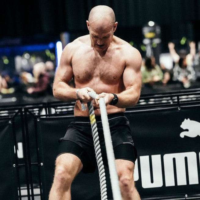 Muscular man pulling ropes on a Hyrox event - apmzee 